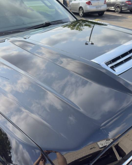 The same Silverado hood after paint correction and ceramic coating, reflecting the sky