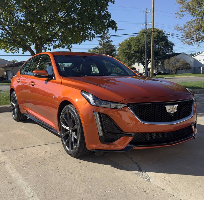 Orange Cadillac sedan with dark wheels parked in the sun