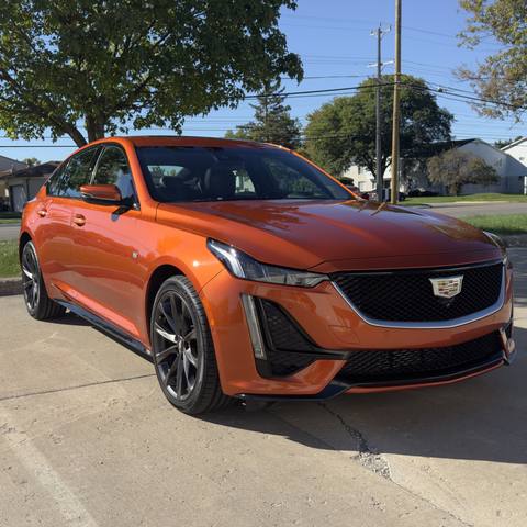 Orange Cadillac sedan with dark wheels parked in the sun