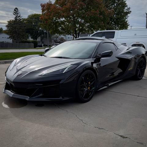 Black mid-engine Corvette with black wheels parked outside