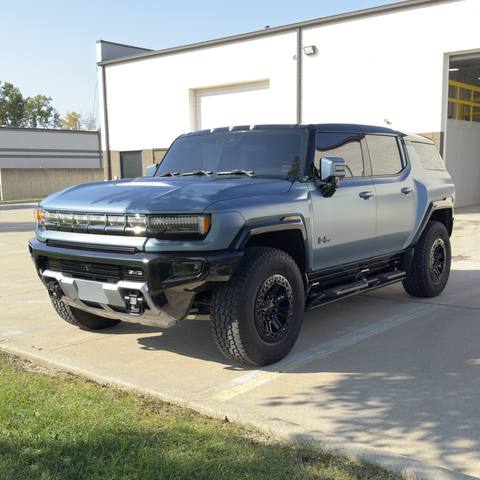 Blue gray GMC Hummer pickup parked outside the shop
