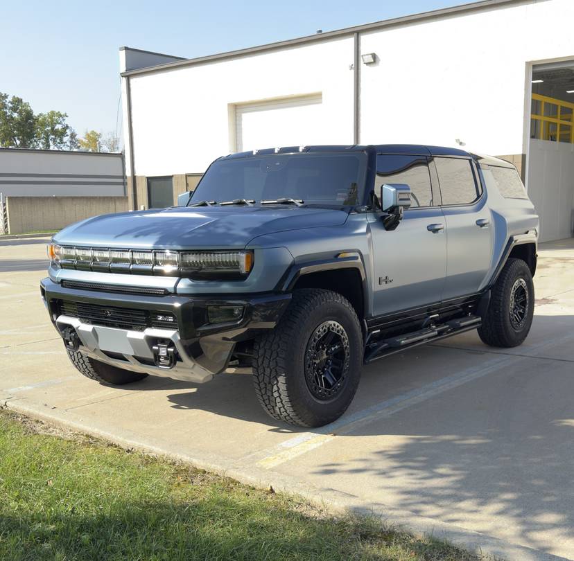 Blue gray GMC Hummer pickup parked outside the shop