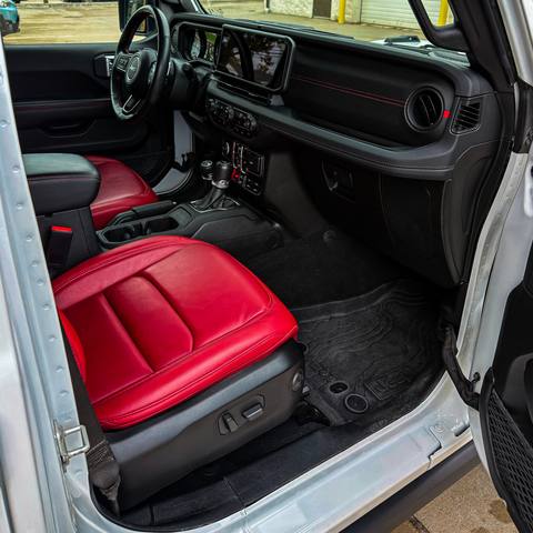 Clean Jeep interior with red leather seats, seen through the open driver door
