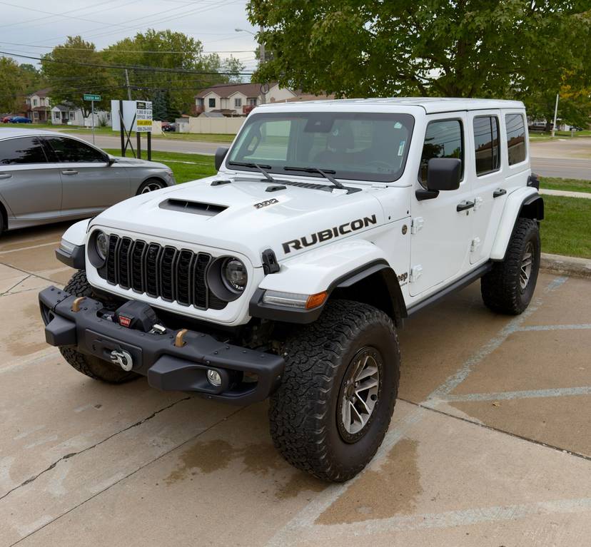 White four door Jeep Rubicon with a front winch, freshly washed