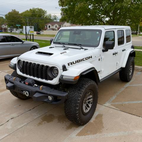 White four door Jeep Rubicon with a front winch, freshly washed