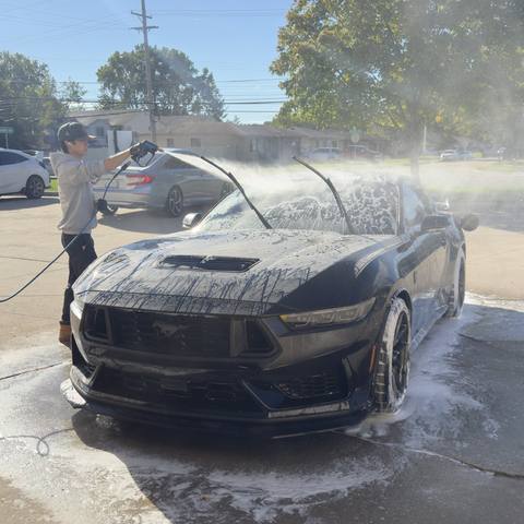 A Refresh My Ride technician foam washing a black Mustang