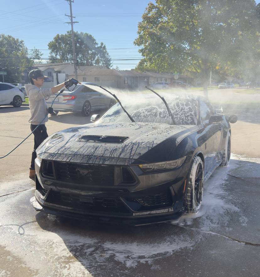 A Refresh My Ride technician foam washing a black Mustang