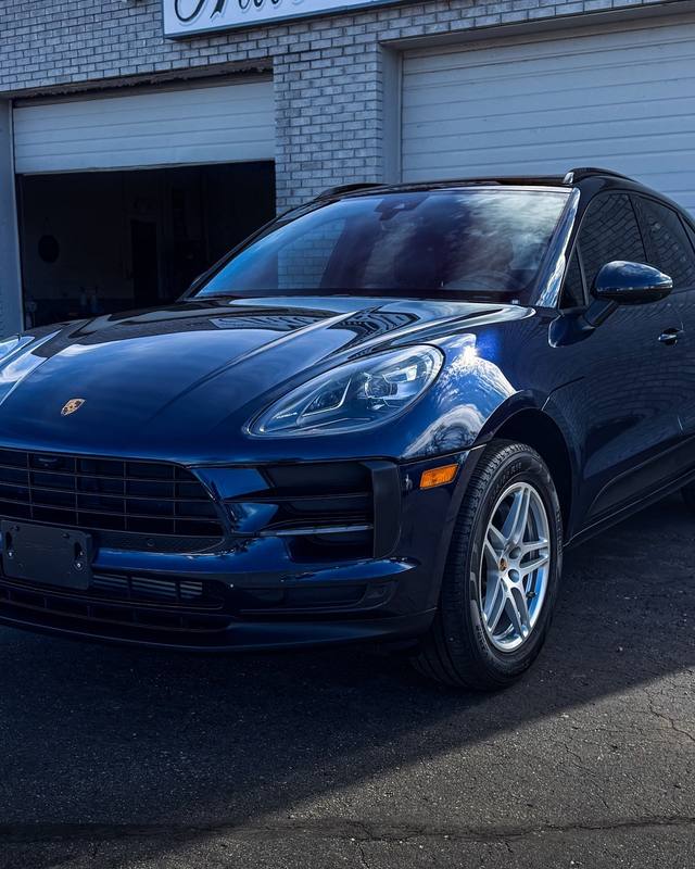 Blue Porsche SUV in front of the shop bay doors