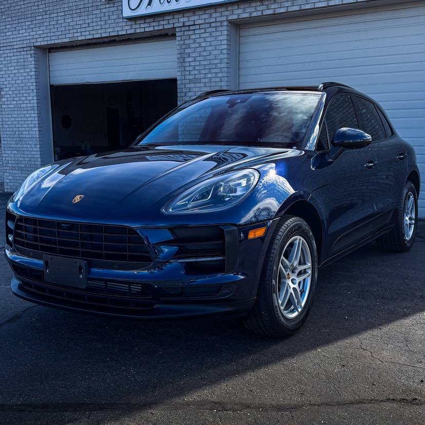 Blue Porsche SUV in front of the shop bay doors